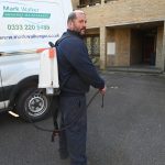 White male Mark Walker gardener wearing weed killer harness beside van